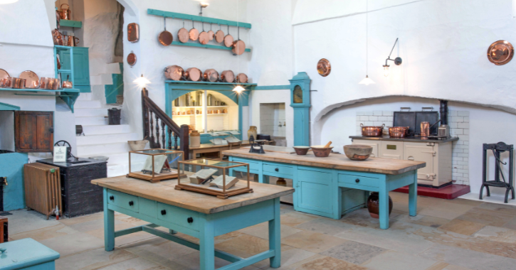 White and turquoise medieval kitchen inside Raby Castle filled with lots of copper pans